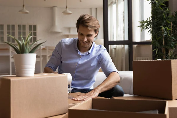 Sonriente joven empacando pertenencias en cajas de cartón. — Foto de Stock