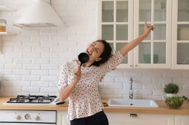 Dertsiz, mutlu, genç bir kadın mutfakta şarkı söylüyor..