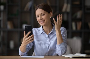 Hoşnutsuz bir kadın telefon ekranına bakıyor, kötü haberler okuyor.