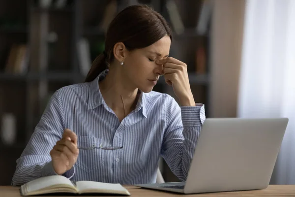 筋疲力尽的年轻女人摘下眼镜，感到眼睛紧张 — 图库照片