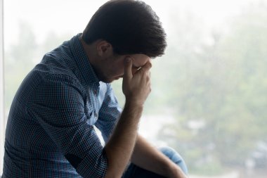 Depresyonda olan milenyum adamı kafaya dokunur, yüzünü kapatır.