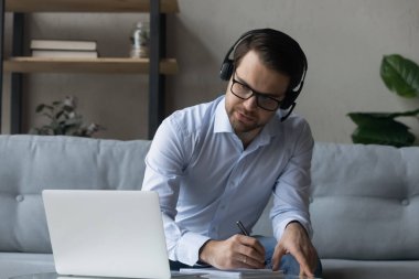 Kablosuz kulaklık takan ciddi bir yetişkin mesafe öğrencisi.