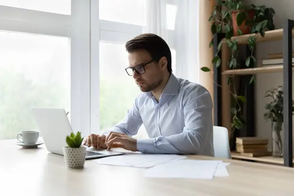 Serious millennial empresario que trabaja en el ordenador portátil en la oficina — Foto de Stock