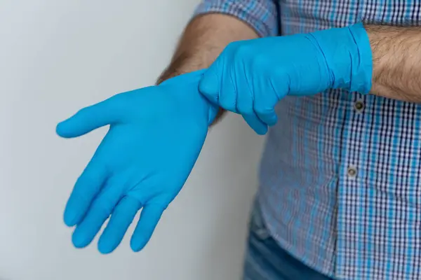 Handen van de mens met blauwe beschermende rubberen handschoenen — Stockfoto