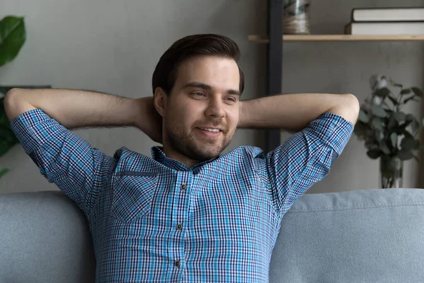 Thoughtful smiling guy relaxing on couch, looking away and smiling — Stock Photo, Image