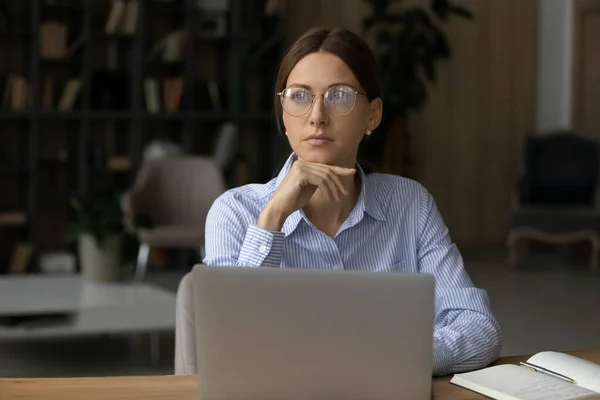 戴眼镜的多愁善感的女人望着旁边，从笔记本电脑上分散注意力 — 图库照片