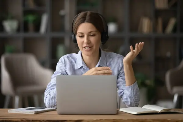 Mujer de negocios sonriente en auriculares usando computadora portátil, consultando al cliente en línea — Foto de Stock