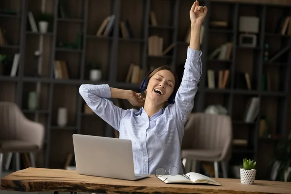 Mujer de negocios muy alegre en los auriculares cantando, sentado en el escritorio con el ordenador portátil — Foto de Stock