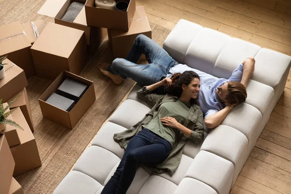 Lächelndes Millennial-Familienpaar ruht auf gemütlicher Couch. — Stockfoto