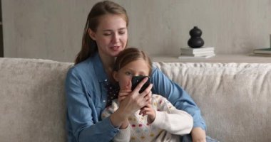 Küçük kız. Annesi cep telefonu kullanıyor. İnternette vakit geçiriyor.