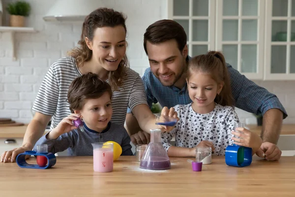 Coppia felice e fratelli bambini impegnati nell'apprendimento del gioco chimico — Foto Stock