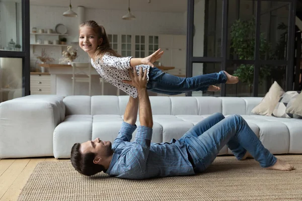 Aufgeregtes kleines Mädchen und glücklicher Papa spielen Flugzeug — Stockfoto