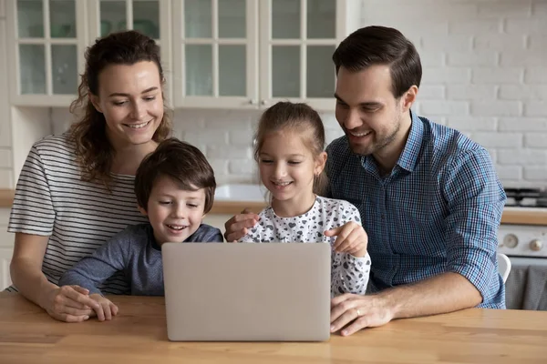 Familia feliz usando el ordenador portátil en la cocina, disfrutando del tiempo libre juntos —  Fotos de Stock