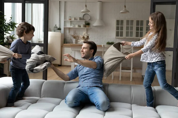 Papá emocionado y niños hermanos locos peleando con almohadas — Foto de Stock