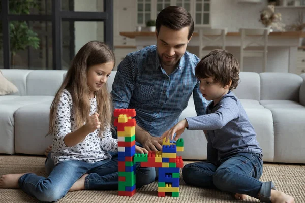 Buon papà e due bambini che giocano insieme sul pavimento caldo — Foto Stock