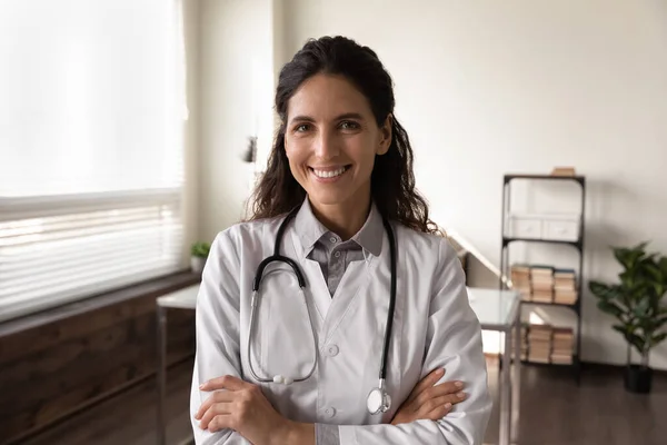 Felice medico GP femminile in camice bianco guardando la fotocamera — Foto Stock