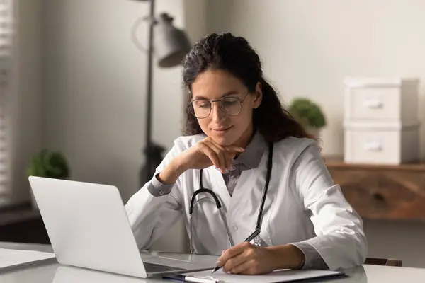 Focalizzato sorridente medico GP dando consultazione online a distanza sul computer portatile — Foto Stock