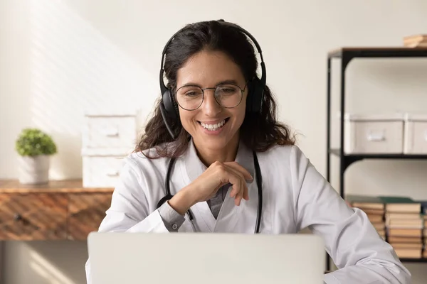 Gelukkige vriendelijke vrouwelijke arts in hoofdtelefoon chatten met de patiënt — Stockfoto
