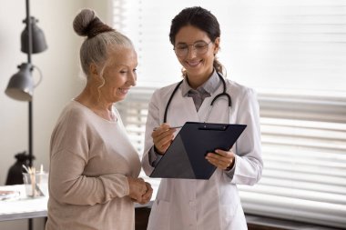 Mutlu pratisyen hekim terapisti olgun 70 'li yaşlardaki kadın hastaya yastık gösteriyor.