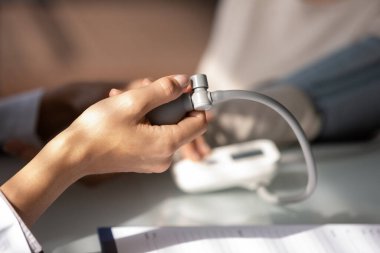 Doktorun eli kan basıncını ölçmek için sphygmomanometre kullanıyor.