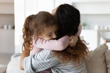 Sevecen küçük kız çocuğu şefkatli anneye sarılıyor..