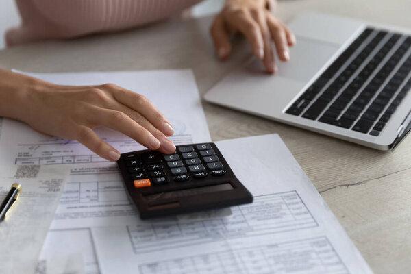 Close up smart young woman calculating domestic utility bills.