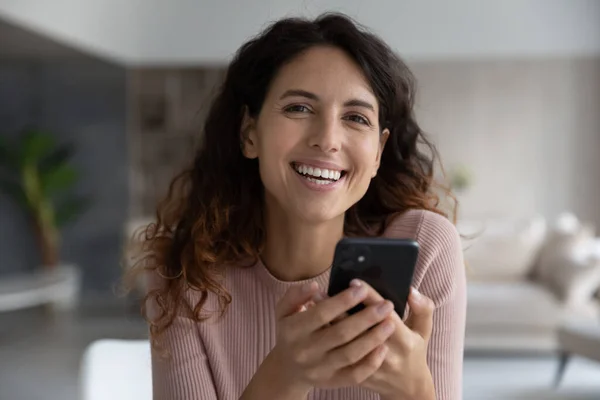 Portret van lachende vrolijke jonge Spaanse vrouw met mobiele telefoon. — Stockfoto