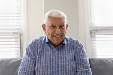 Mutlu yaşlı bir adam dişlek gülümsemesiyle kameraya bakıyor.