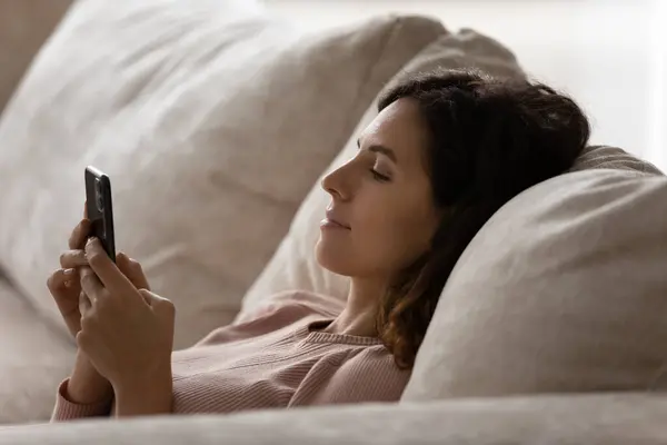 Relaxado jovem mulher usando celular em casa. — Fotografia de Stock