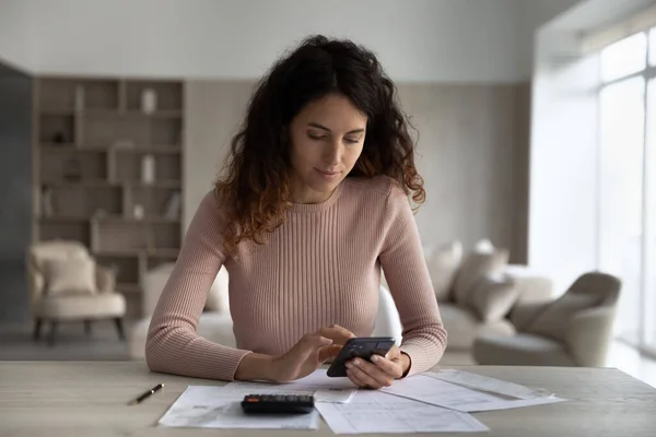 Presupuesto de planificación de hermosa mujer joven concentrado usando el teléfono celular. — Foto de Stock