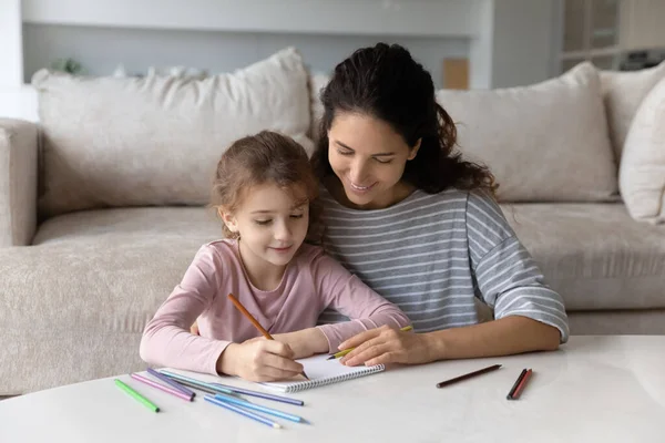 Jovem mãe ensinando pequena filha escrevendo cartas. — Fotografia de Stock