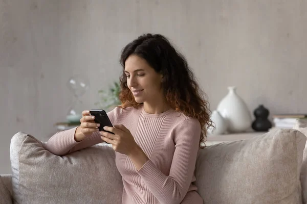 Ontspannen jonge Latijnse vrouw die betrokken is bij het gebruik van smartphone. — Stockfoto