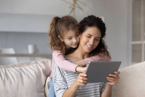 Feliz niña pequeña y madre cariñosa usando tableta. — Foto de Stock