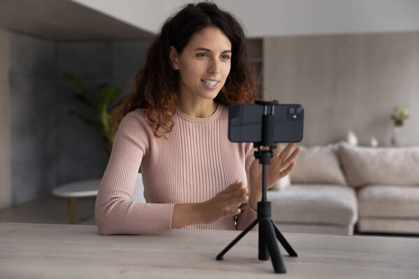 Улыбающаяся латиноамериканка записывает видео на веб-камеру мобильного телефона.