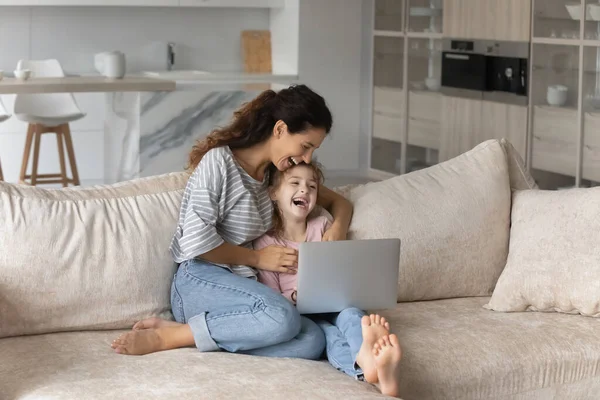 Feliz joven madre y pequeña hija viendo dibujos animados divertidos. — Foto de Stock
