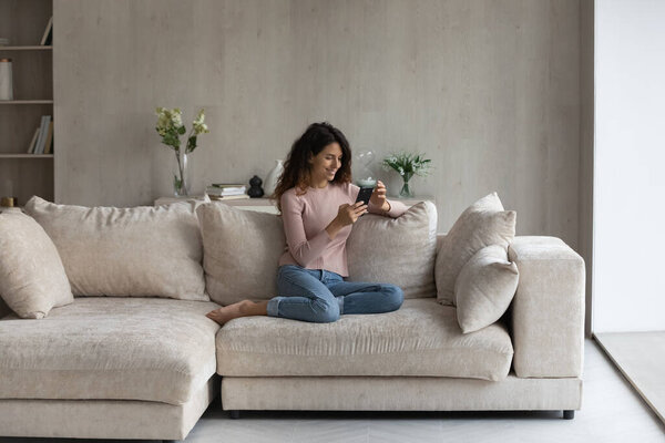 Relaxed young woman using cellphone at home.