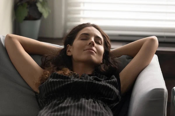 Unelias rauhallinen latino asunnonomistaja nainen lepää sohvalla kotona — kuvapankkivalokuva