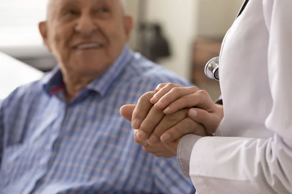 Therapeut im weißen Kittel hält Hand einer optimistischen Seniorin — Stockfoto