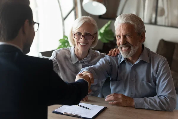 Excited mature couple shaking manager businessman hand at meeting — Stock Photo, Image