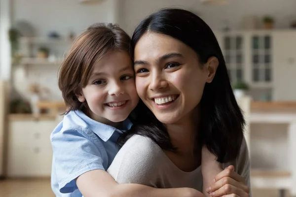 Happy cute small boy cuddling beautiful asian korean mother. — Stock Photo, Image