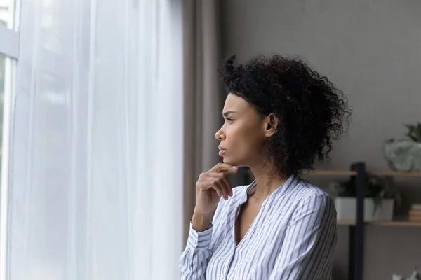 Wanita muda hitam kontemplatif melihat jendela menyentuh dagu berpikir — Stok Foto