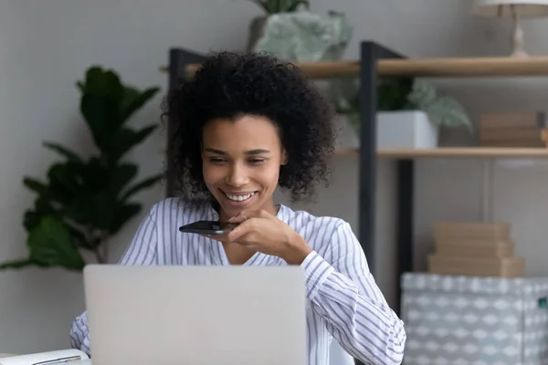 Jovem mulher negra trabalhar usando aplicativo de voz laptop no telefone — Fotografia de Stock