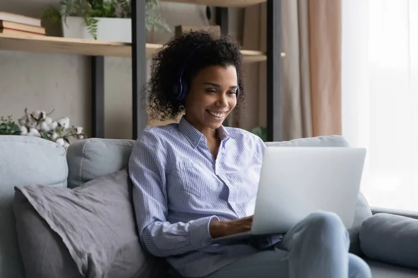 Sorridente giovane signora nera in cuffia studiare online utilizzando il computer portatile — Foto Stock