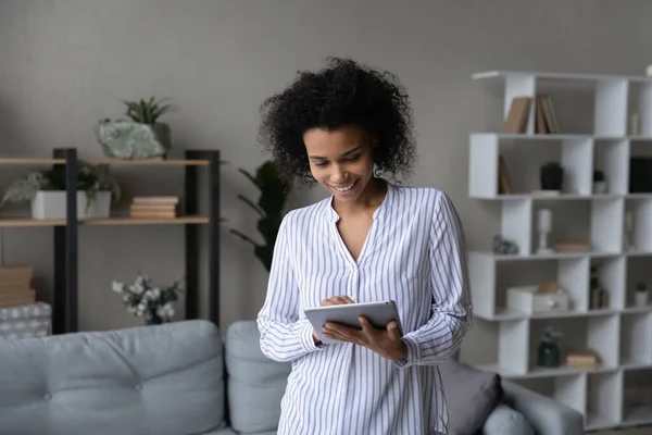 Young african woman work online on tablet at living room