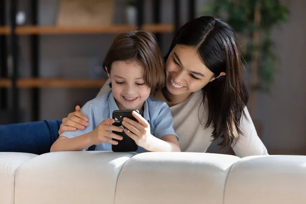 Affectionate happy young asian mother using cellphone with small kid. — Stock Photo, Image