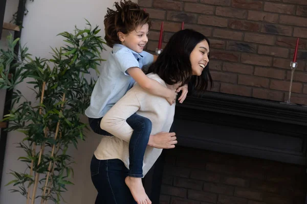 Happy young korean mother holding on back cute son. — Stock Photo, Image
