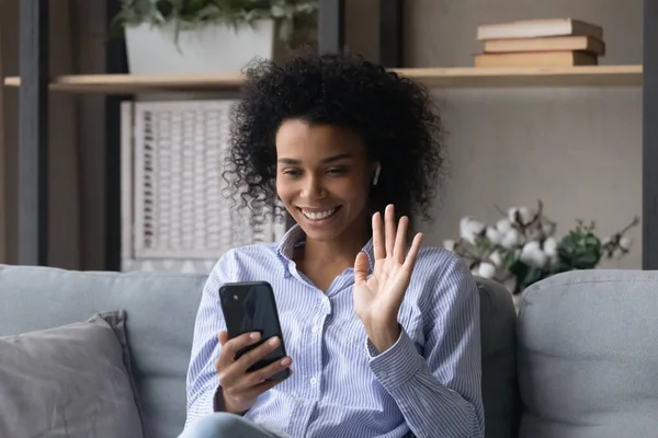 Jeune femme noire dans les écouteurs vague chat main par videocall — Photo