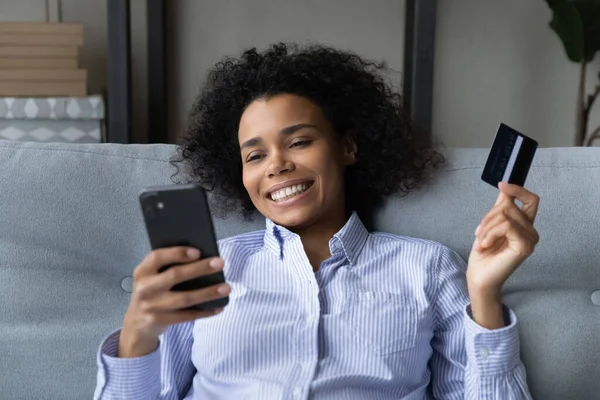Wanita kulit hitam muda memeriksa saldo kartu kredit secara online melalui telepon — Stok Foto