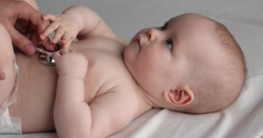 Çocuk doktoru steteskoplu bebeği muayene ediyor.