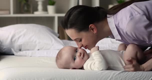 Молодая любящая мать целует в щеку своего сладкого малыша — стоковое видео
